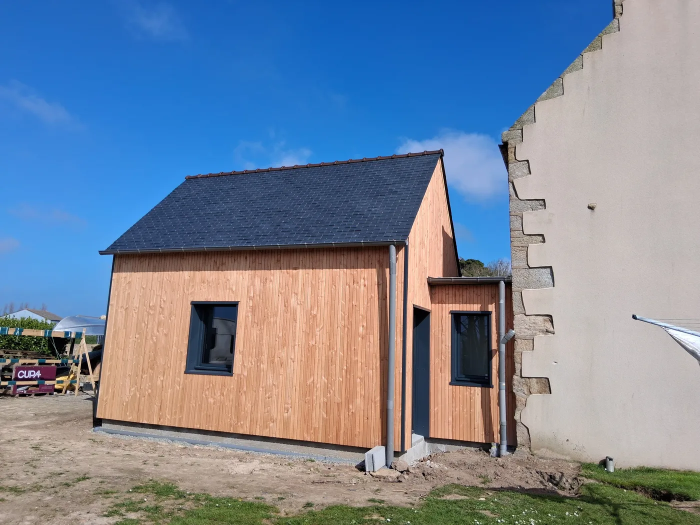 Extension bois à clin vertical adossée à un pignon en pierre près de Brignogan — Coat-Amis Charpente