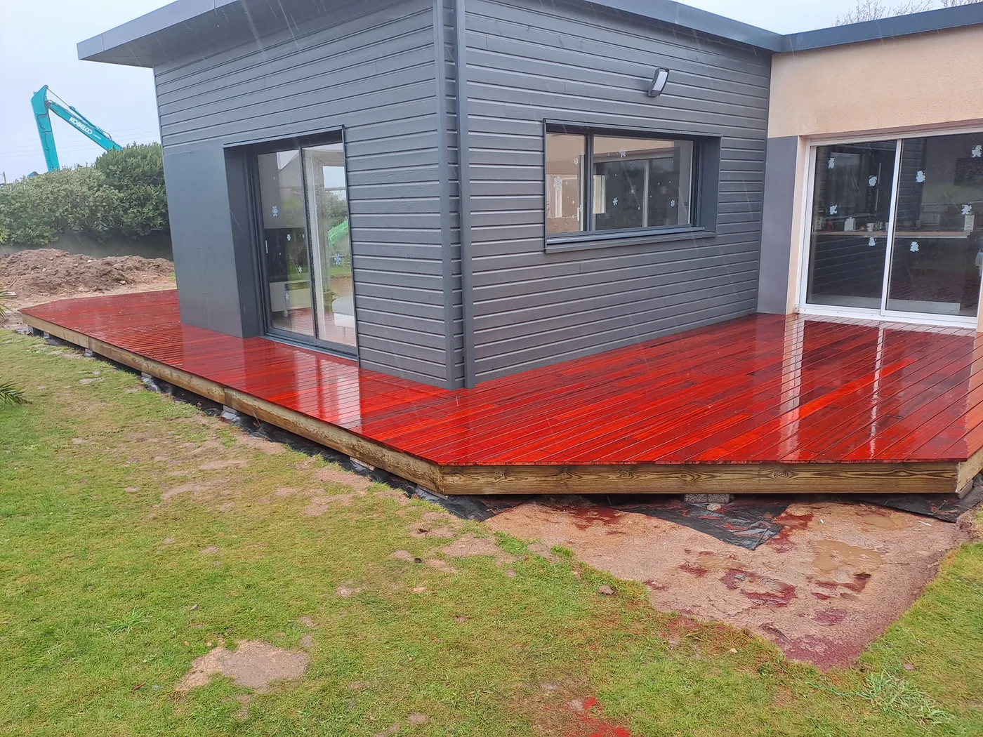 Terrasse bois finition rouge autour d'une extension contemporaine en Finistère Nord — Coat-Amis Charpente